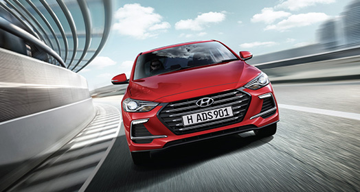 Front view of red Elantra Sport driving on the road