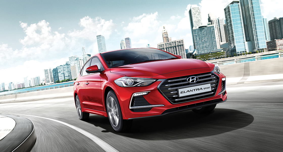 Right side front view of red Elantra Sport driving on the road