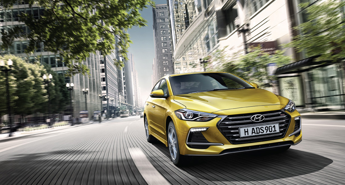 Right side front view of yellow Elantra Sport driving on the street